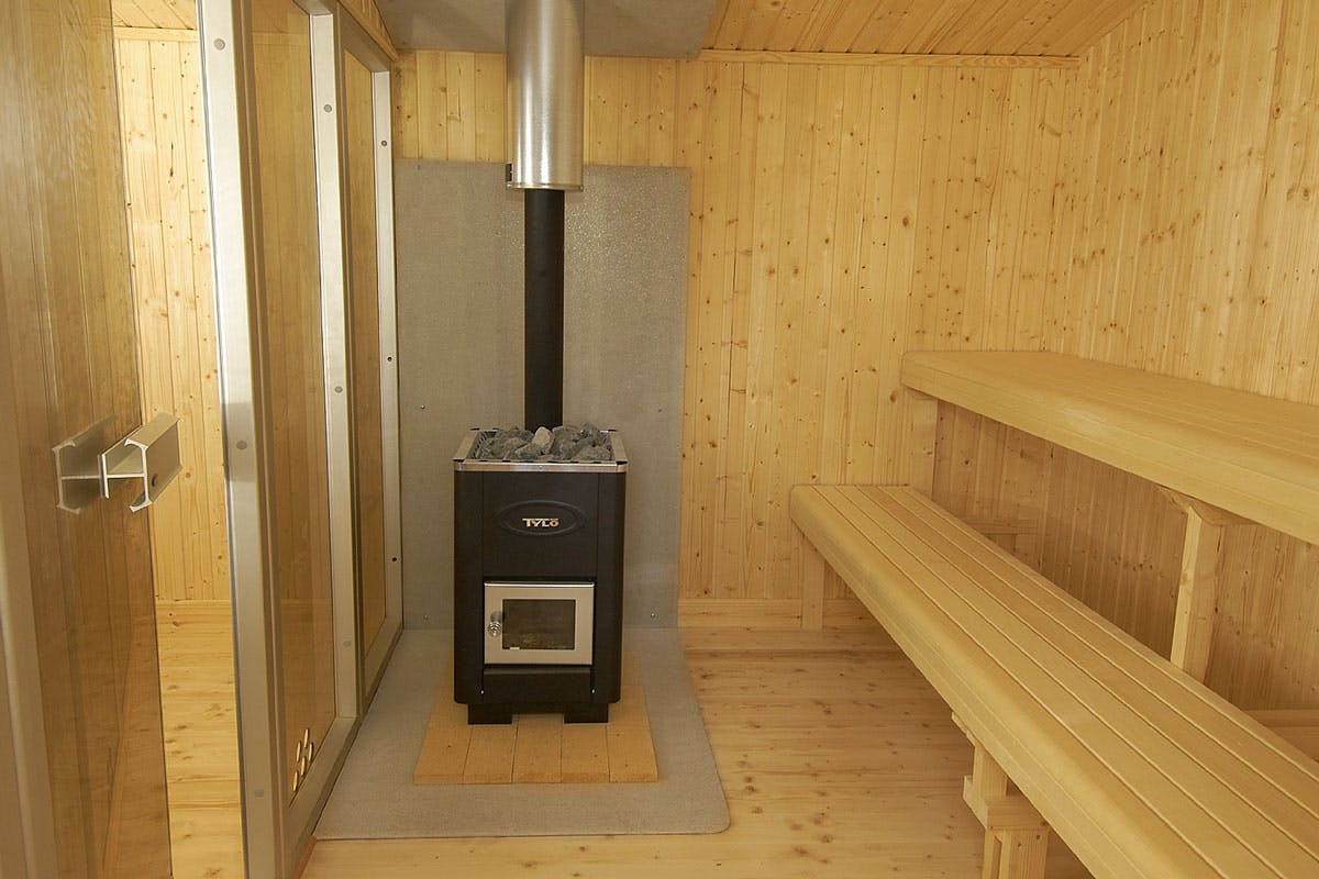 Sauna odottaa ensilöylyjen heittoa. Pitkille lauteille mahtuu 8–10 henkilöä. Sen vuoksi lauteet on varustettu molempiin päihin ja keskelle asennetuilla jaloilla. Puukiuas on tulitiilien ja mineriittilevyn päällä.