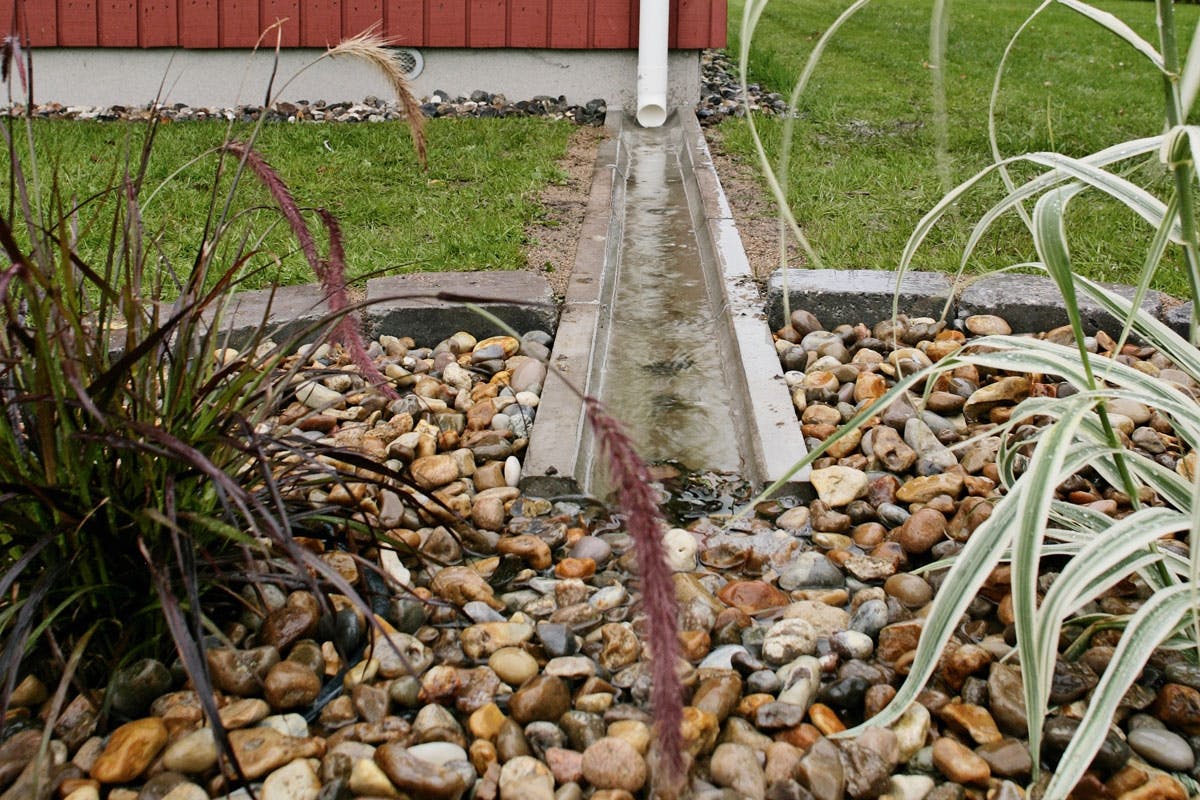 En kanal av hemgjutna betongmoduler är ett praktiskt och snyggt sätt att leda bort regnvatten från huset.
