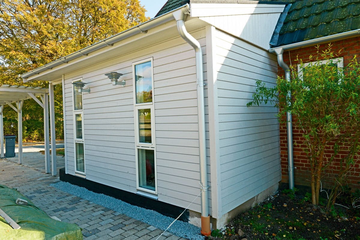 Tillbyggnaden har väggar av trä medan huset har tegelfasad. Det gör inget så länge delarna passar ihop på ett snyggt sätt.