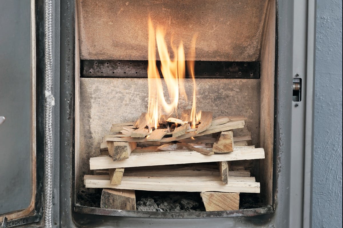 Flammerne fra de små pinde varmer kammeret op, inden ilden når ned til de større stykker. Det giver ren forbrænding.