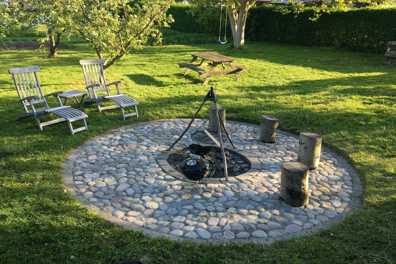 Naturligt bålsted af pigsten <strong>Naturligt bålsted af pigsten</strong><br>
Er du mere til det “naturlige” look, kan du lave et bålsted af pigsten, som er lidt større sten med runde former. Stenene bankes på plads i grus, som lægges ud, når det øverste lag jord er fjernet.
