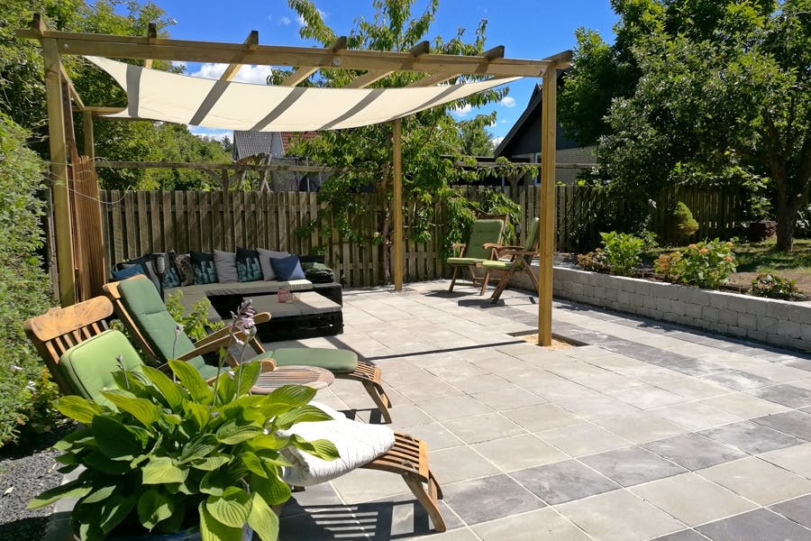Hyggekrok med stein: Flott steinterrasse med pergola og solseil Hyggekrok med stein: Flott steinterrasse med pergola og solseil