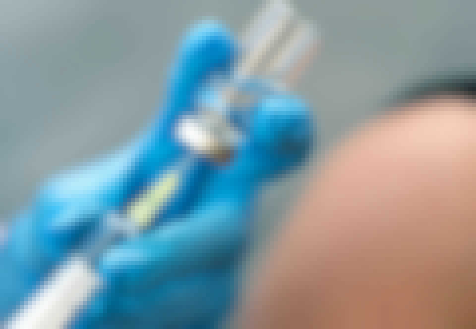 Handskeklædt hånd doserer en kanyle med vaccine. Handskeklædt hånd doserer en kanyle med vaccine.